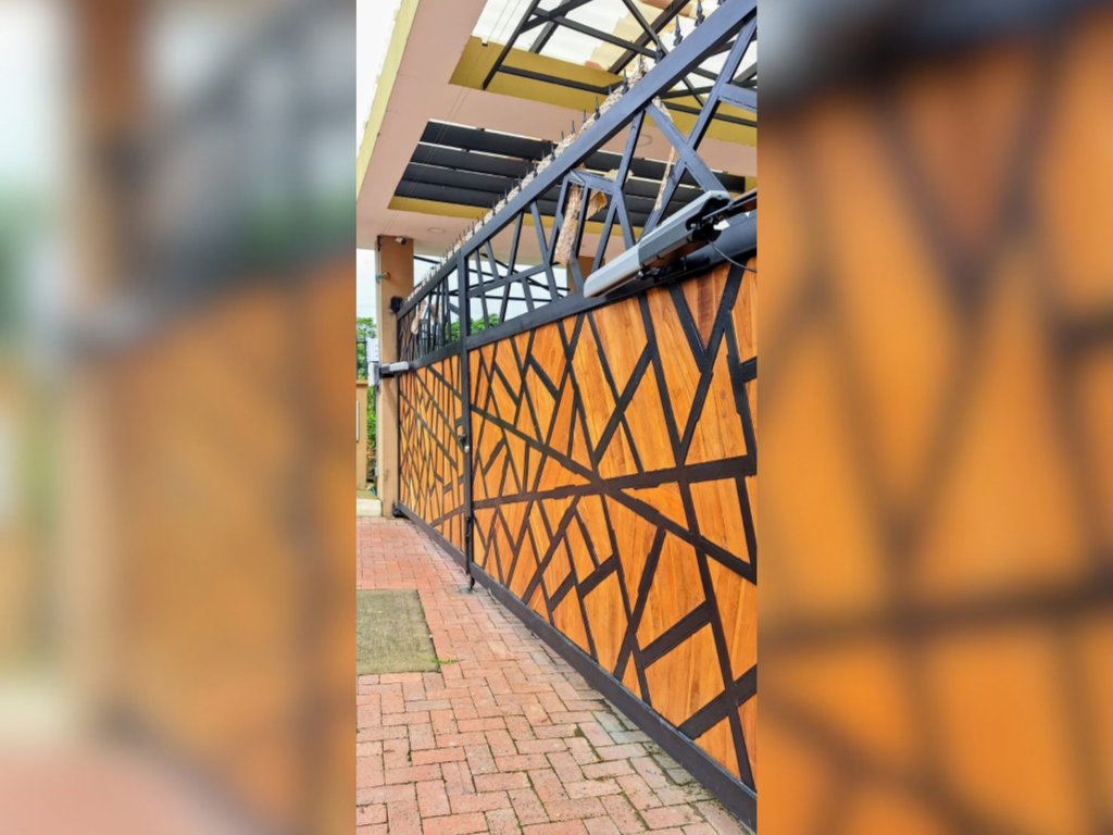 Puerta automática con diseño geométrico de rejas negras y paneles de madera clara
