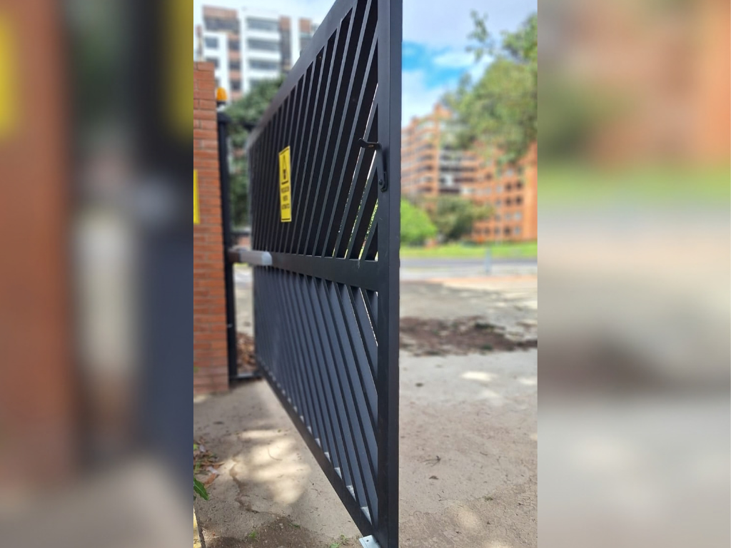Vista lateral de una puerta corredera metálica negra de diseño diagonal abriéndose sobre su riel