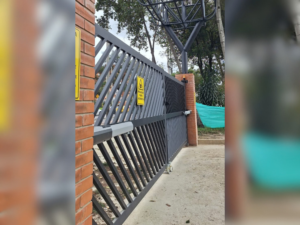 Puerta corredera metálica negra con diseño de barras diagonales instalada en el exterior